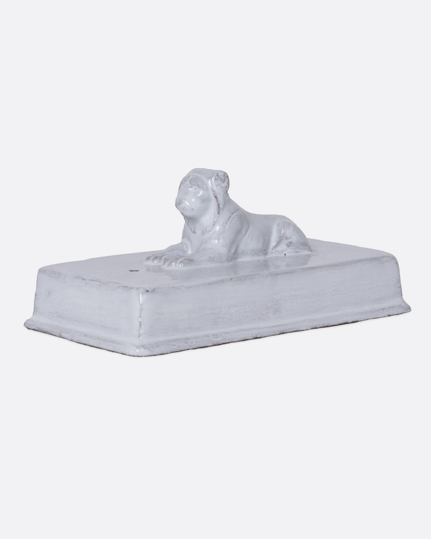 A white rectangular incense holder with a lion on top. Shown from the side. 