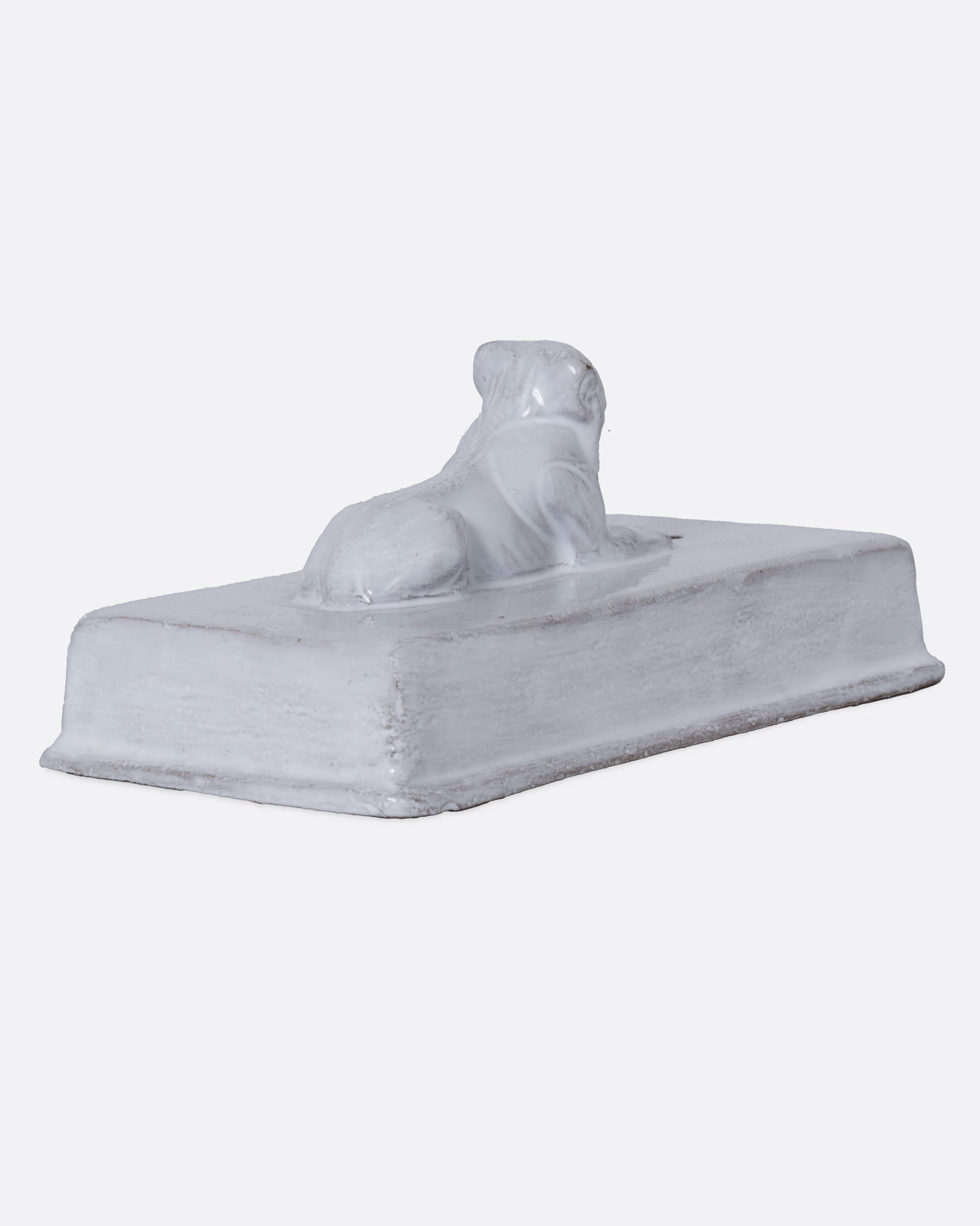 A white rectangular incense holder with a lion on top. Shown from the back.