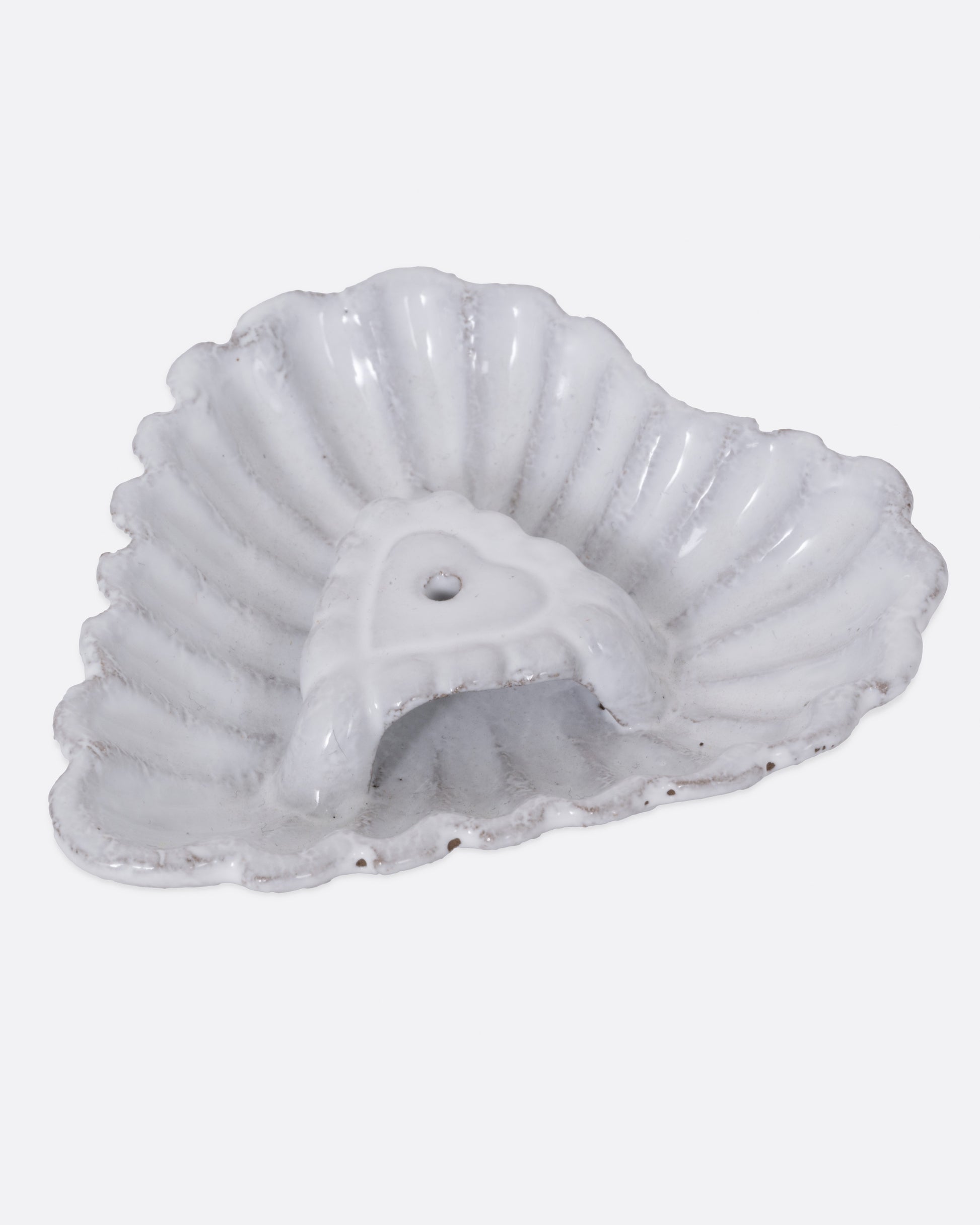 A white heart shaped incense holder, shown from the side. 