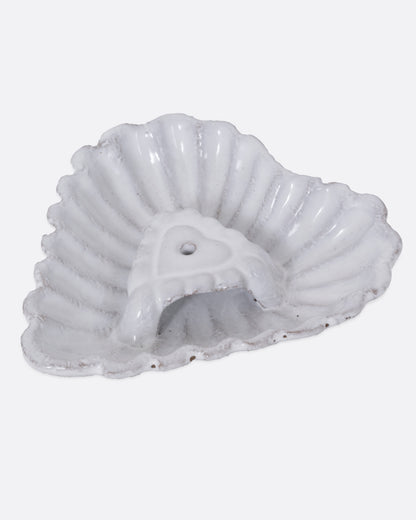 A white heart shaped incense holder, shown from the side. 