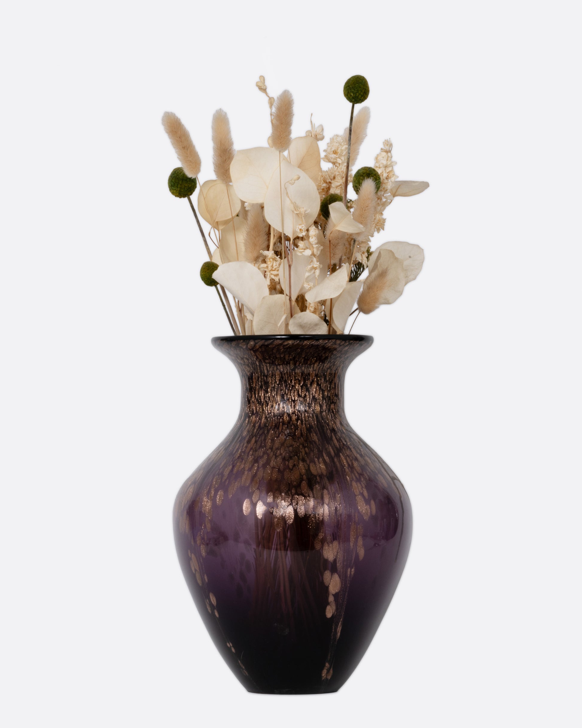 A black, purple, and gold glass vase with an arrangement of dried flowers. Shown from the front.