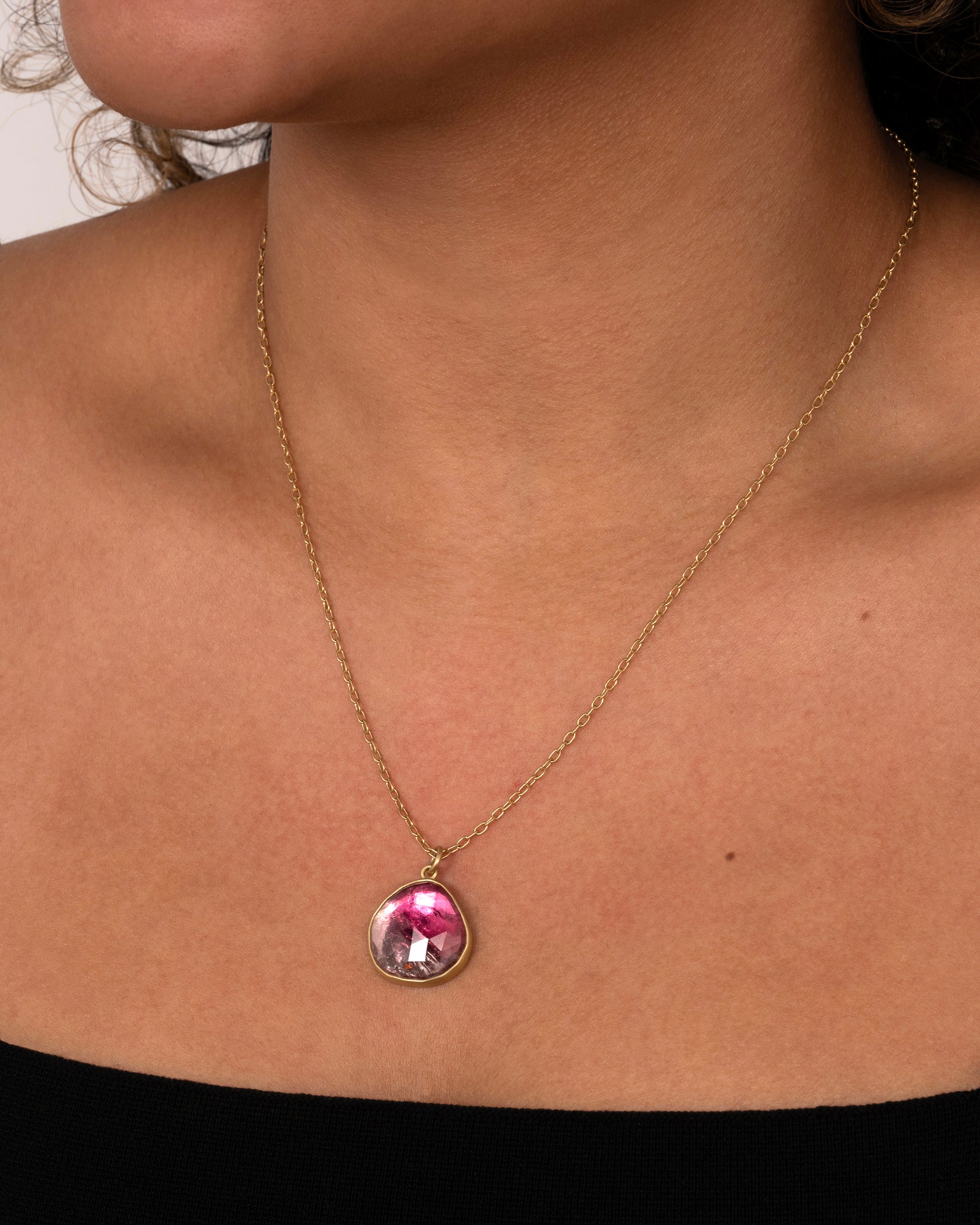 yellow gold necklace with an ombre pink tourmaline shown worn around the neck