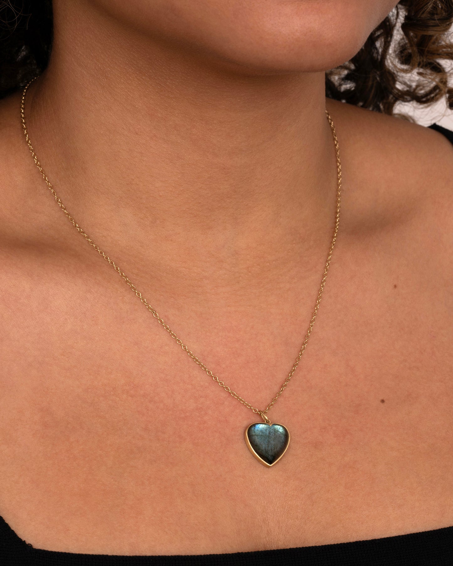 yellow gold necklace with a labradorite heart pendant shown worn around the neck