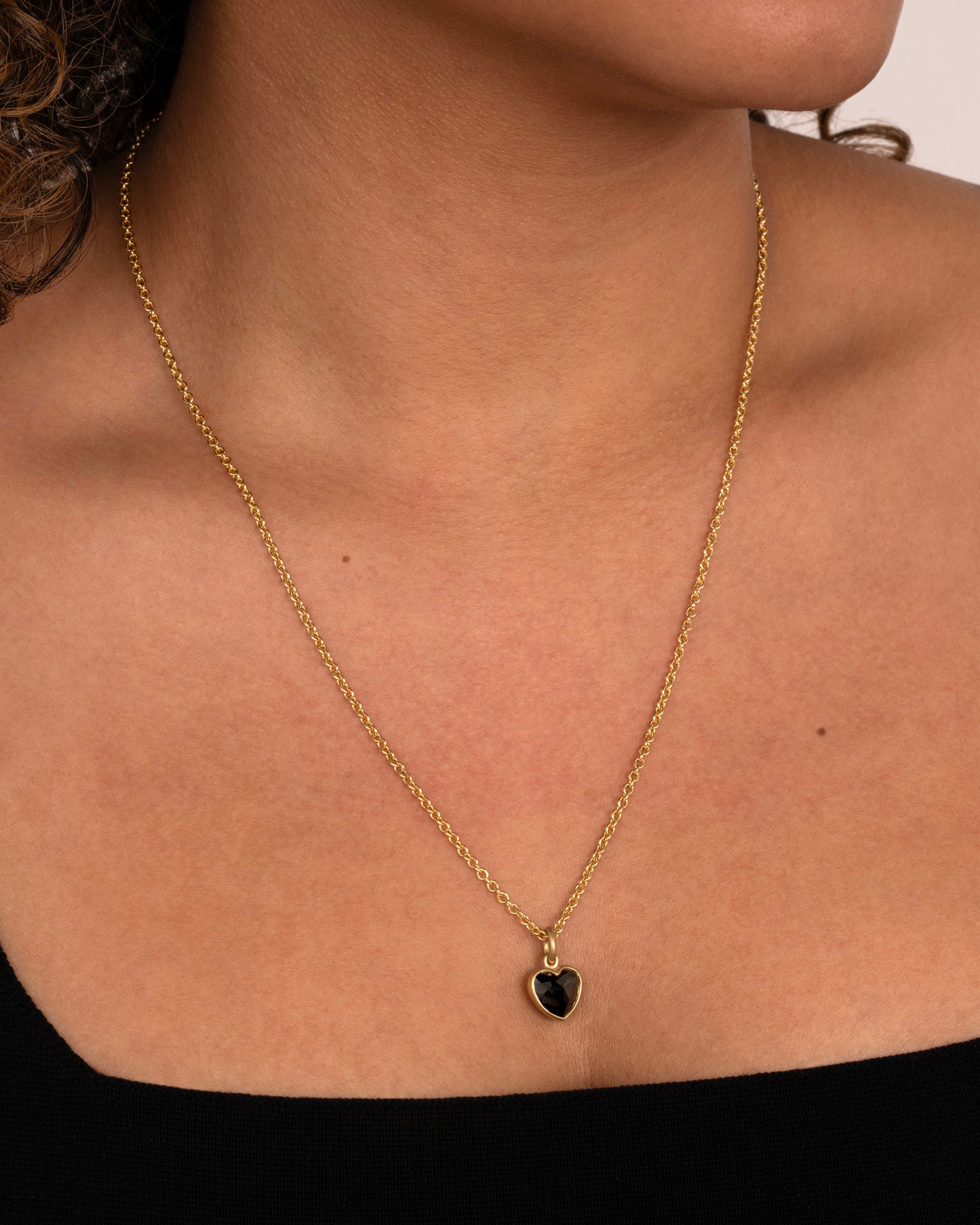 yellow gold necklace with heart shaped black diamond shown worn around a neck