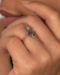 A white and rose gold diamond encrusted abstract ring. Shown worn on a hand.