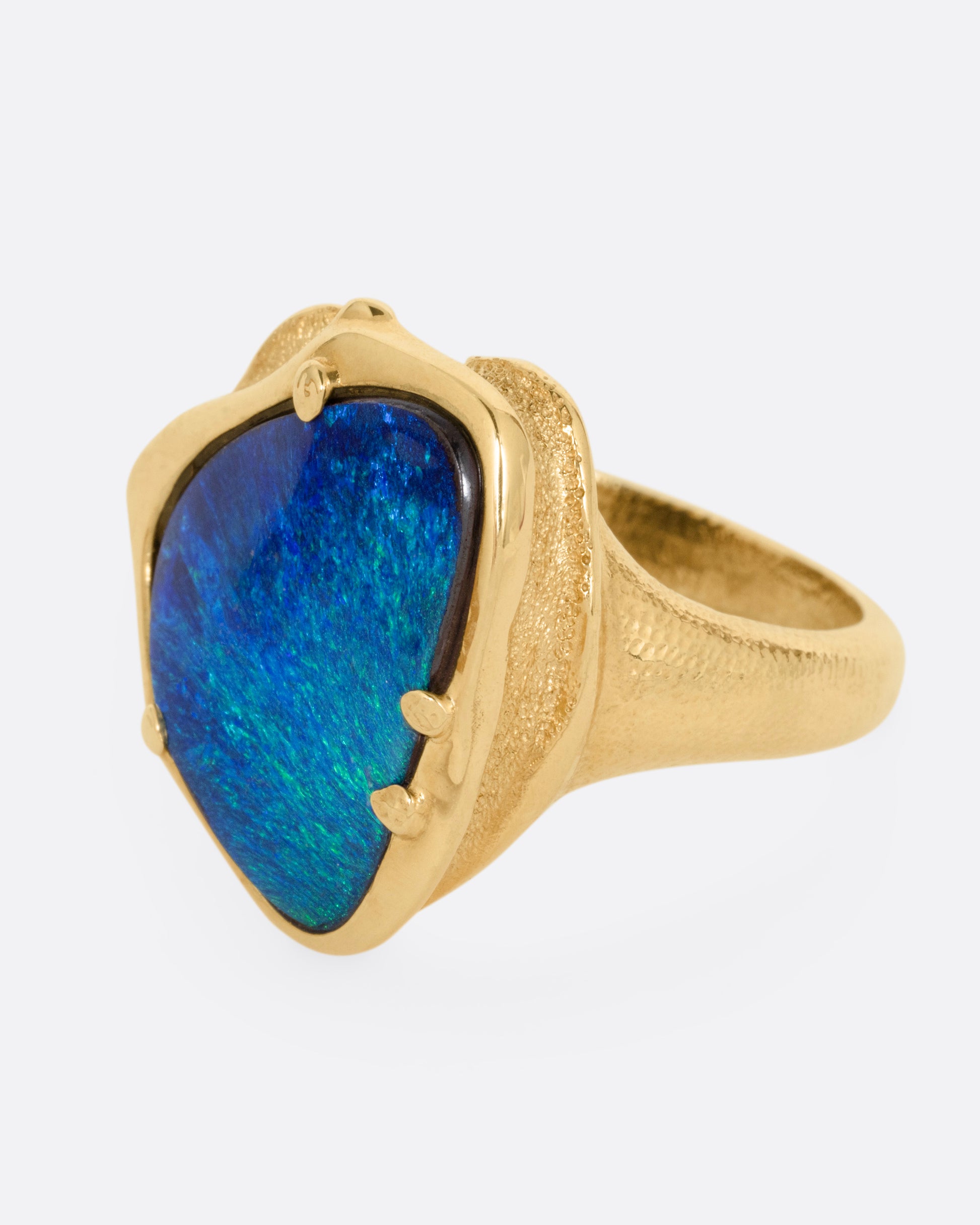 A yellow gold ring with a large boulder opal, shown from the side.