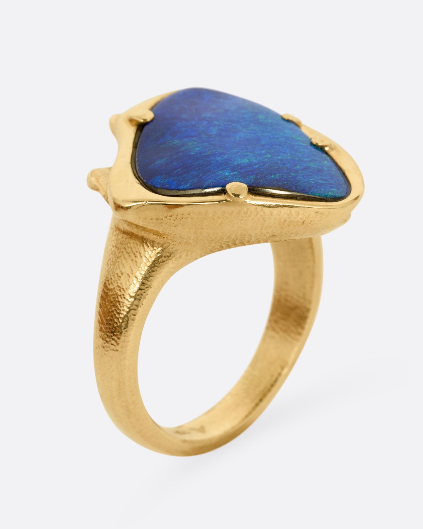 A yellow gold ring with a large boulder opal, shown from the side standing up.