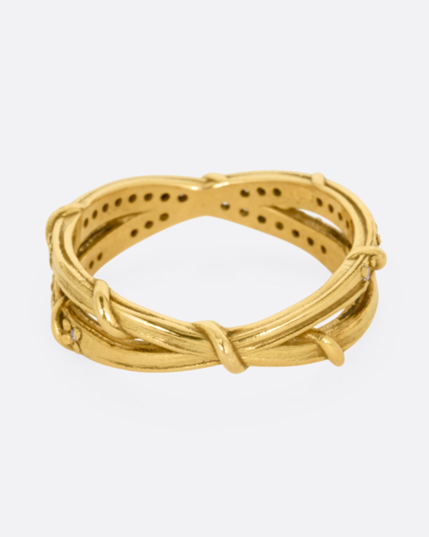 A yellow gold ring with two eternity bands intersecting at the middle and wrapped in vines and colorless diamonds. Shown from the back.