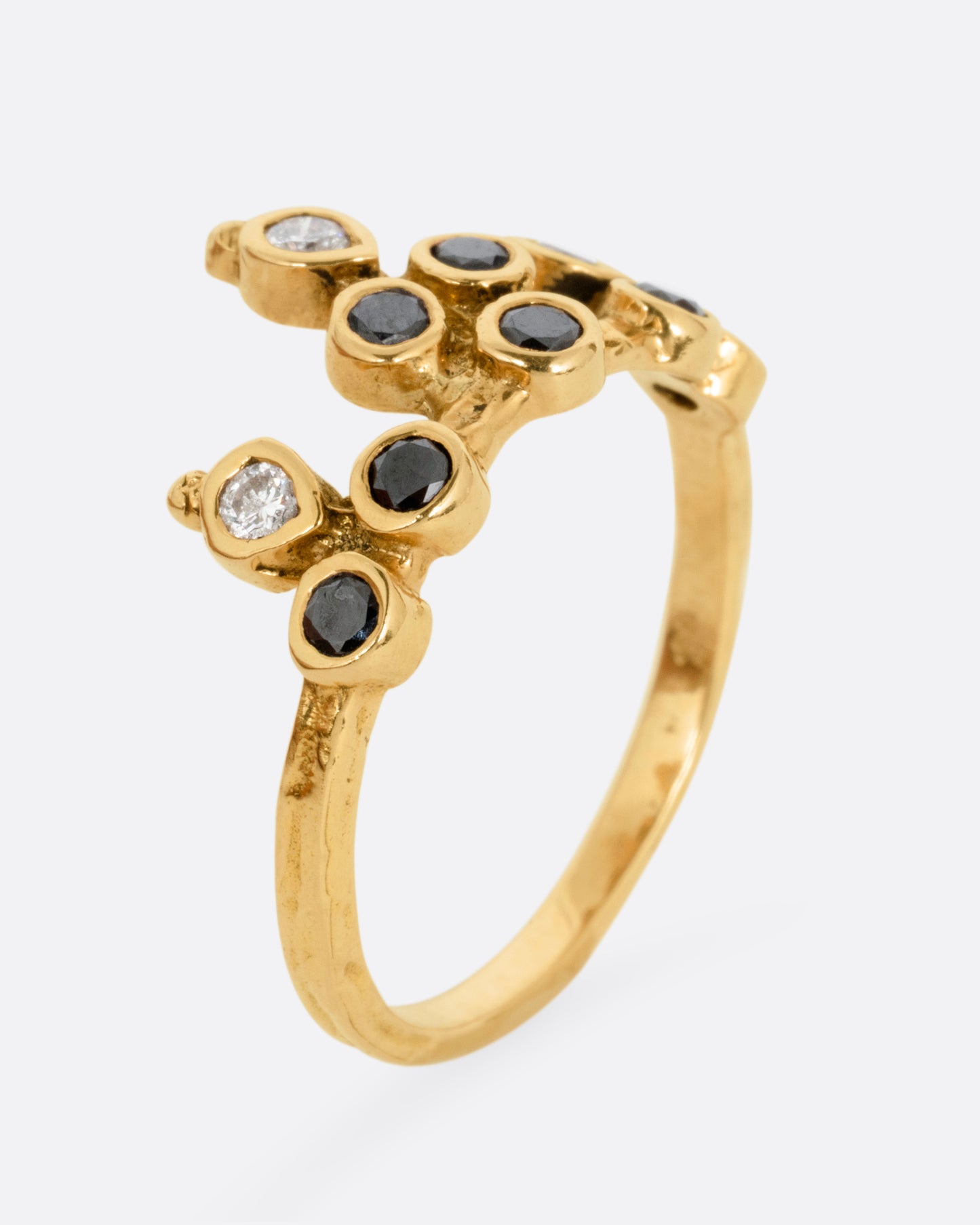 A yellow gold tiara ring with white and black diamonds, shown standing up from the side.