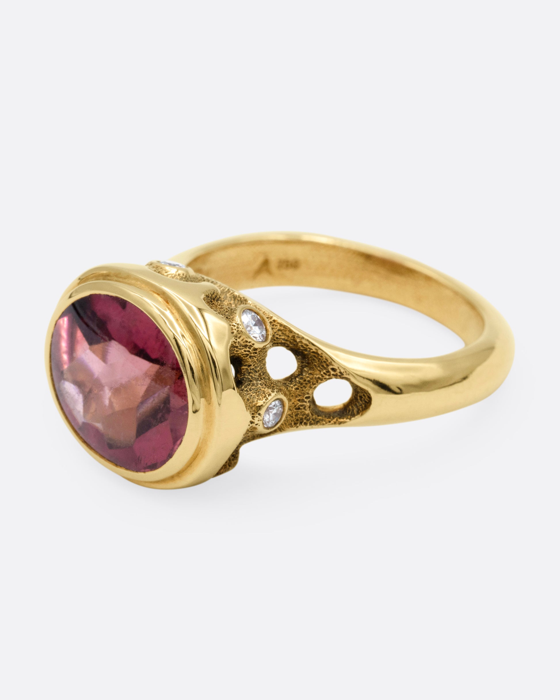 A yellow gold ring with a pink tourmaline and diamond accents. Shown from the side.