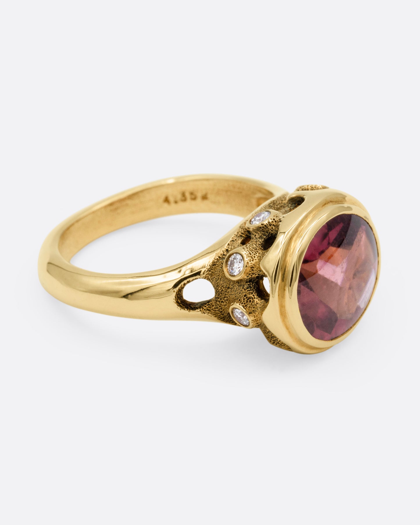 A yellow gold ring with a pink tourmaline and diamond accents. Shown from the side.