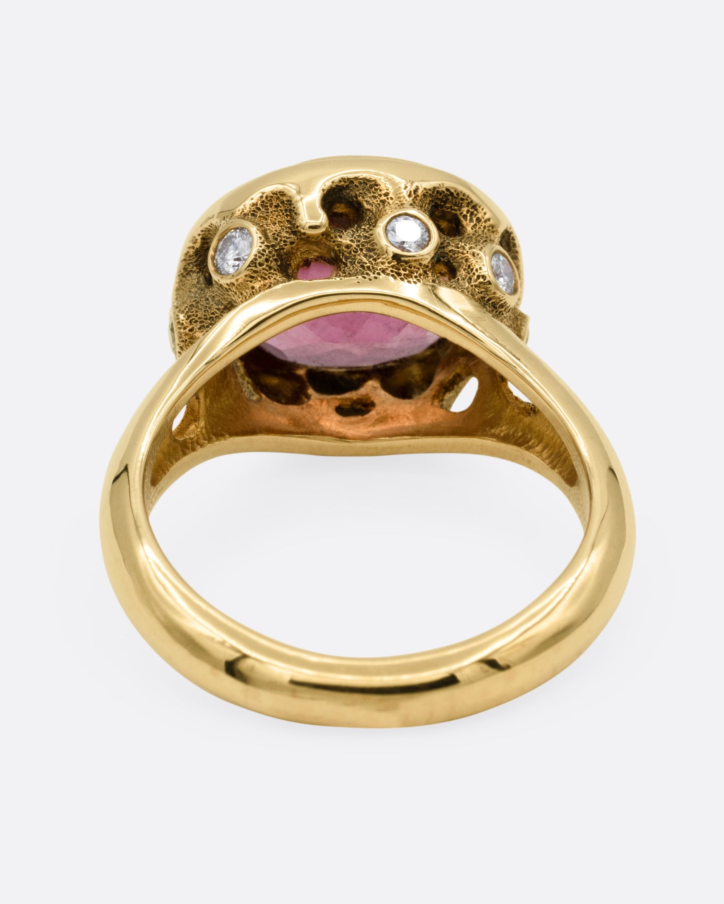 A yellow gold ring with a pink tourmaline and diamond accents. Shown from the back.