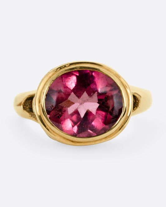 A yellow gold ring with a pink tourmaline and diamond accents. Shown from the front.