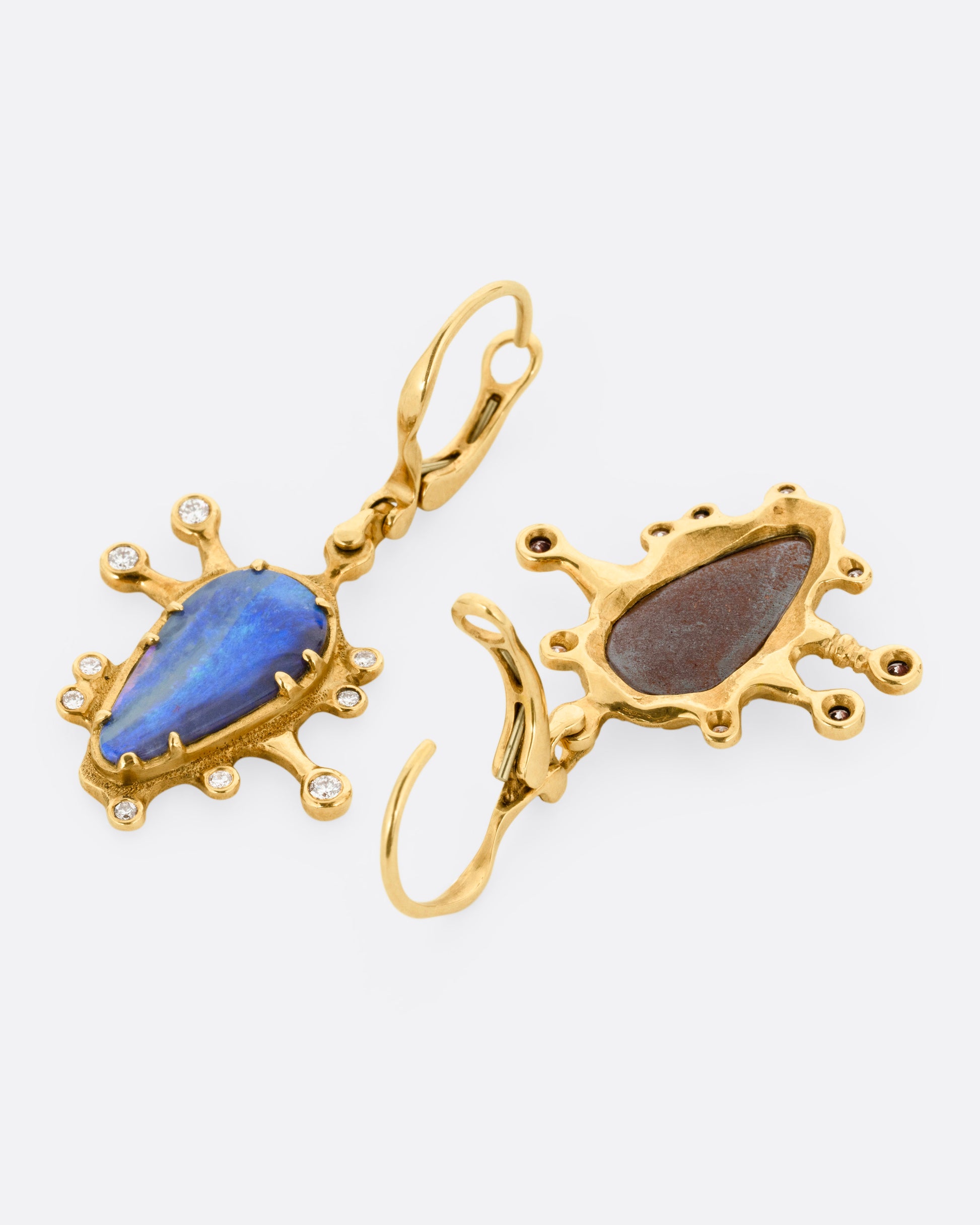 A pair of yellow gold drop earrings with bezel set boulder opals with diamonds protruding along the edges. One earring is shown from the back open, the other is shown from the front.