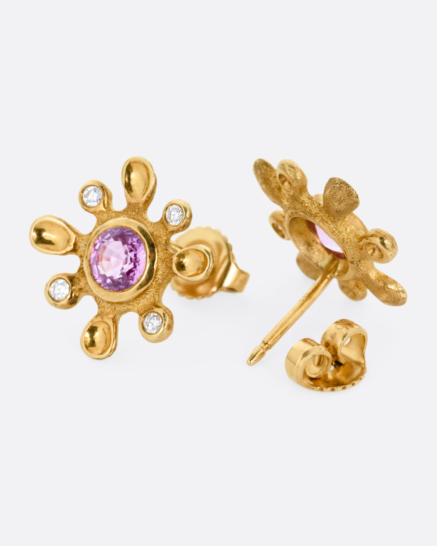 A pair of yellow gold diamond and sapphire flower stud earrings. One earring is shown from the front, the other open from the back.