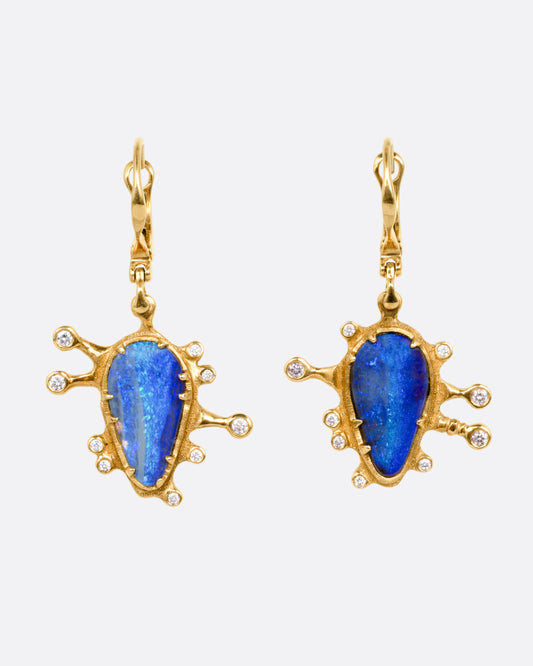 A pair of yellow gold drop earrings with bezel set boulder opals with diamonds protruding along the edges, shown from the front.