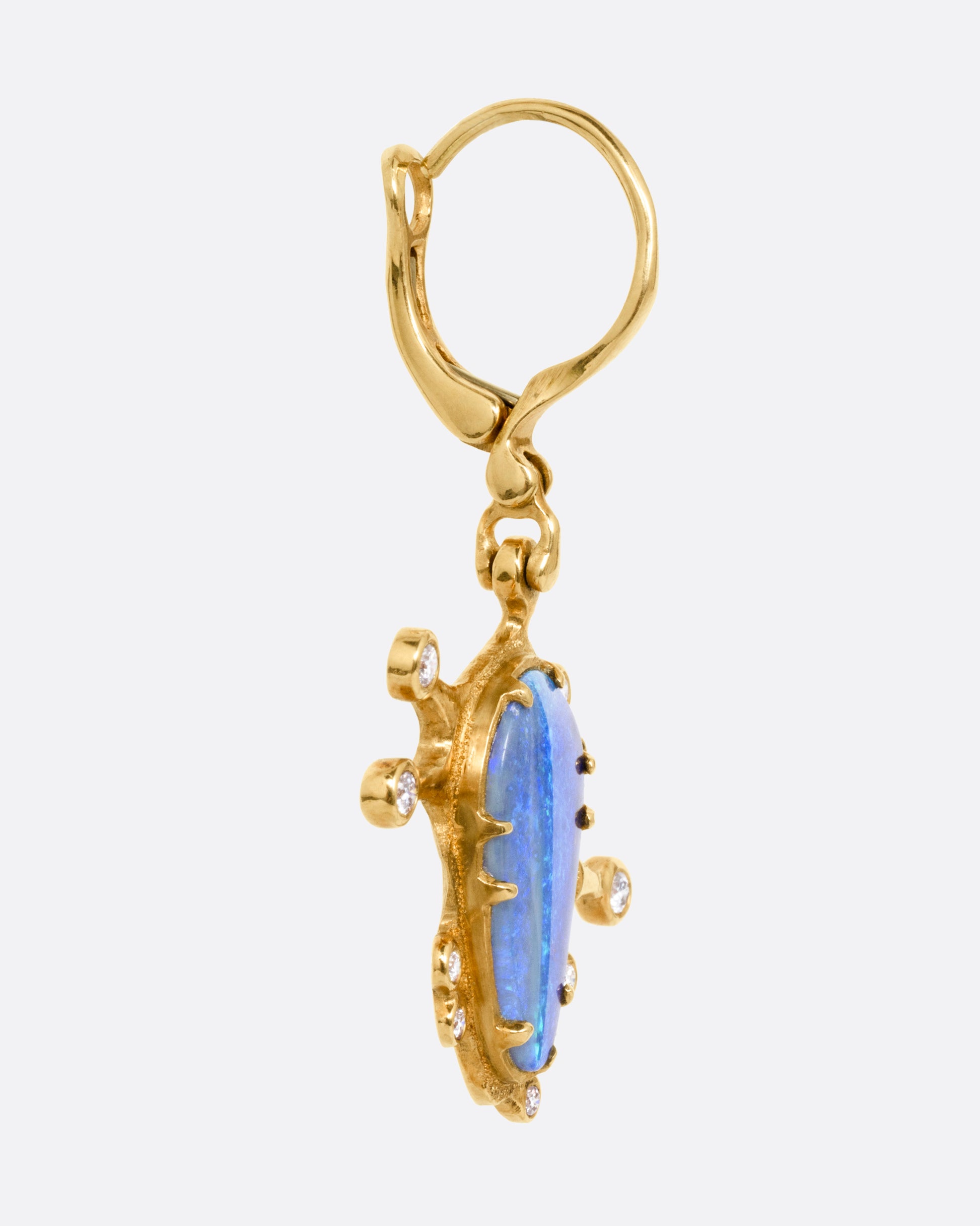A yellow gold drop earring with a bezel set boulder opal with diamonds protruding along the edges, shown from the side.