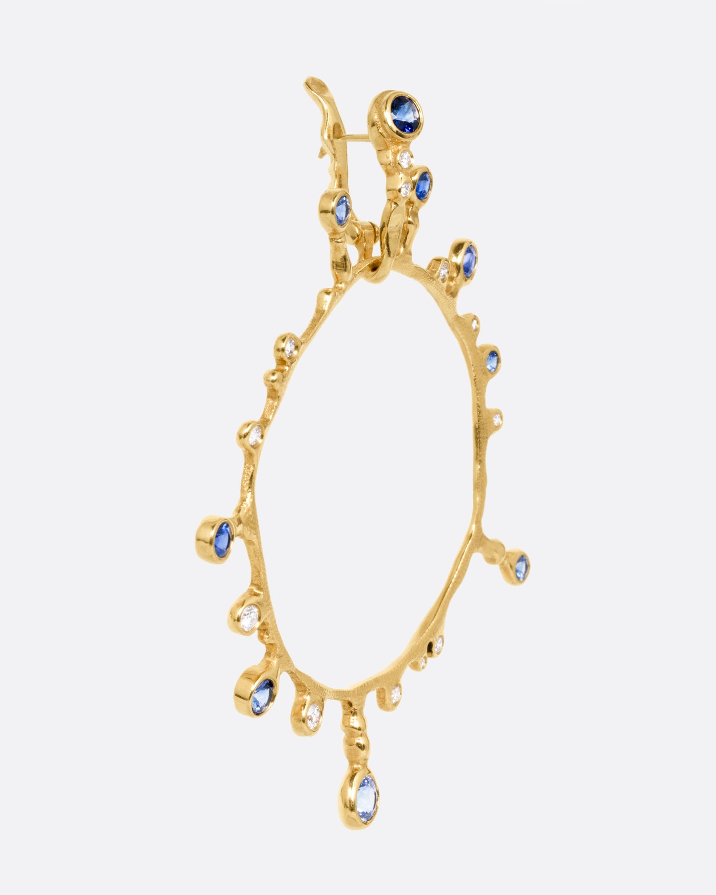 A yellow gold hoop sunburst earring with diamonds and sapphires. Shown from the side.