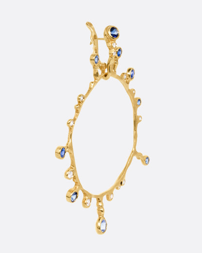 A yellow gold hoop sunburst earring with diamonds and sapphires. Shown from the side.
