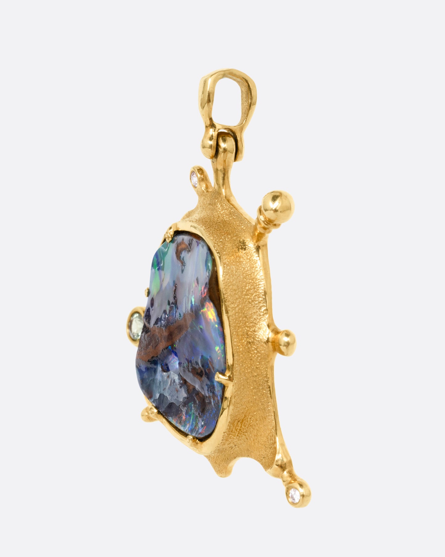 A yellow gold pendant with a boulder opal and diamonds and sapphires along its edges, shown from the side.