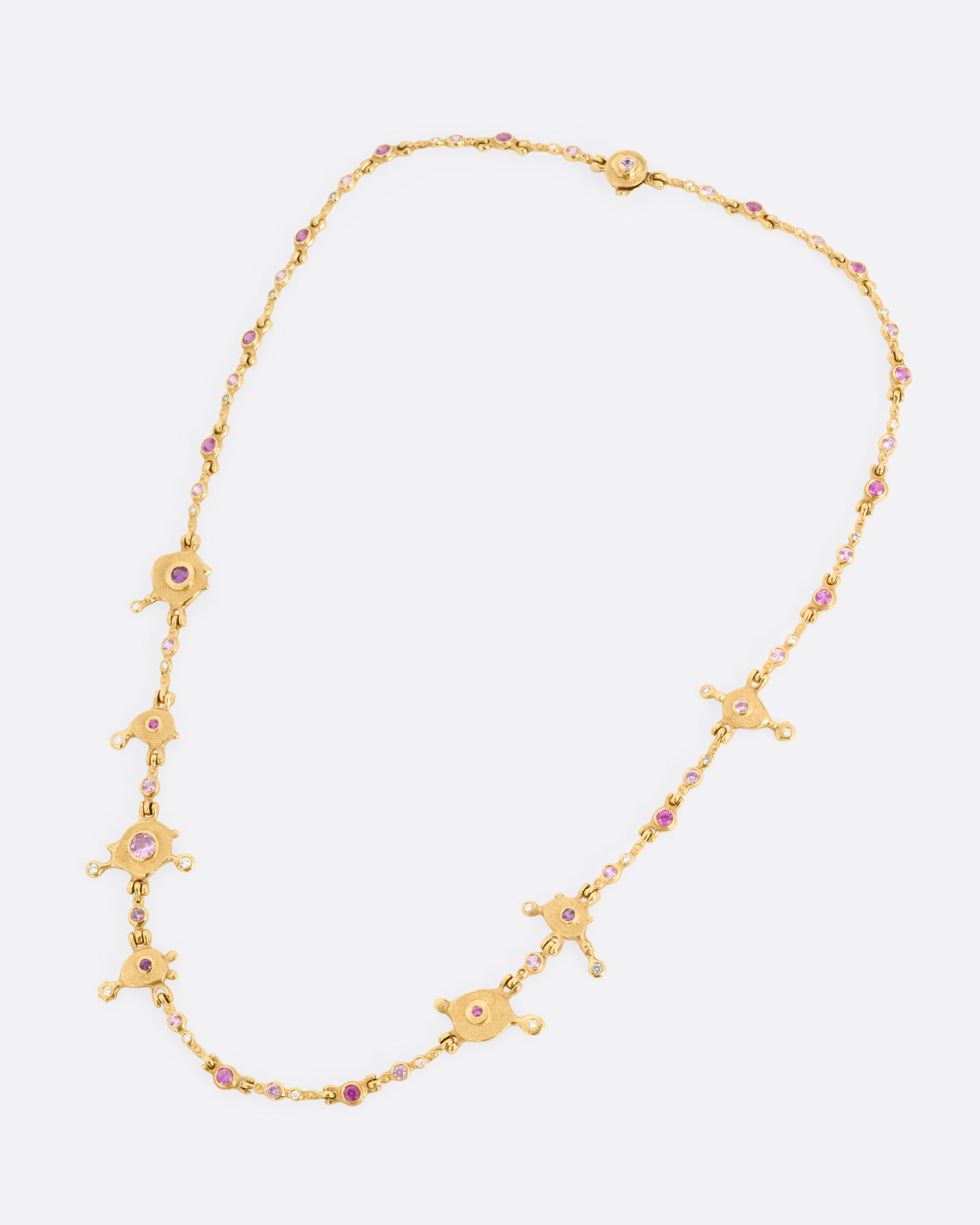 A yellow gold necklace with purple sapphires and diamonds set in handmade stations, shown from the front.