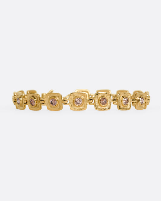 A yellow gold bracelet with squared stations, each with a brown diamond. Shown from the front.