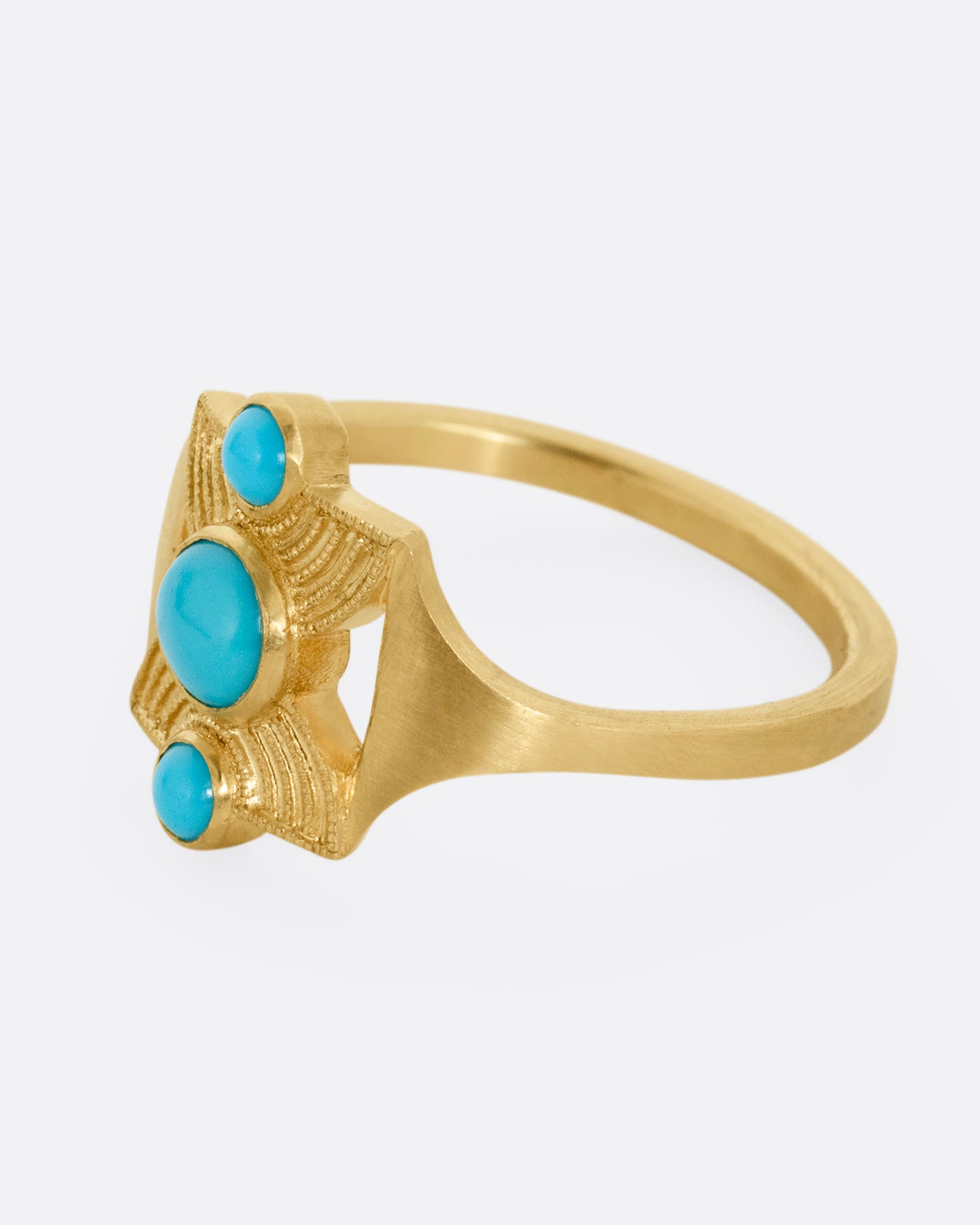 A yellow gold hourglass shaped ring with three stacked bezel set turquoises. Shown from the side.