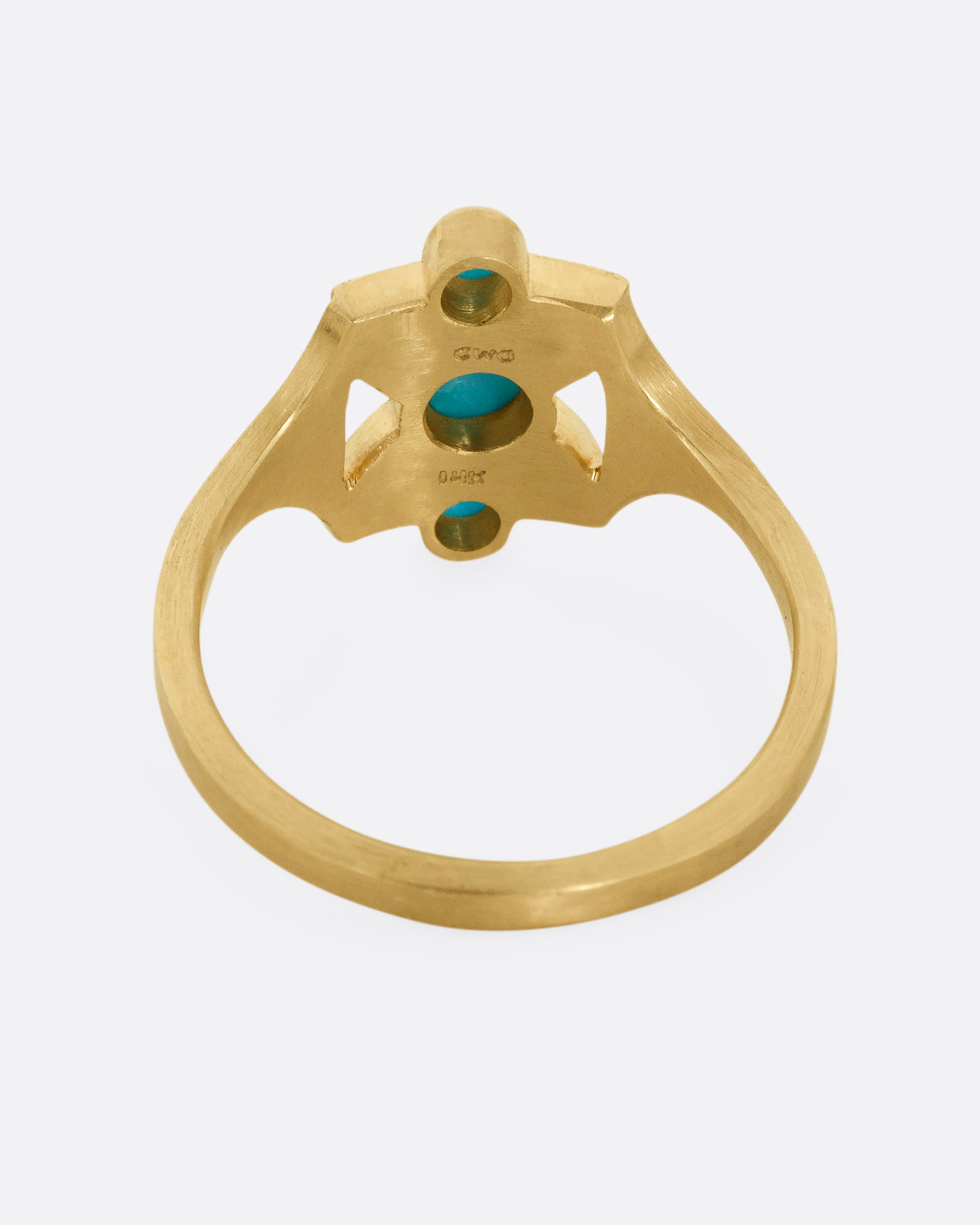 A yellow gold hourglass shaped ring with three stacked bezel set turquoises. Shown from the back.