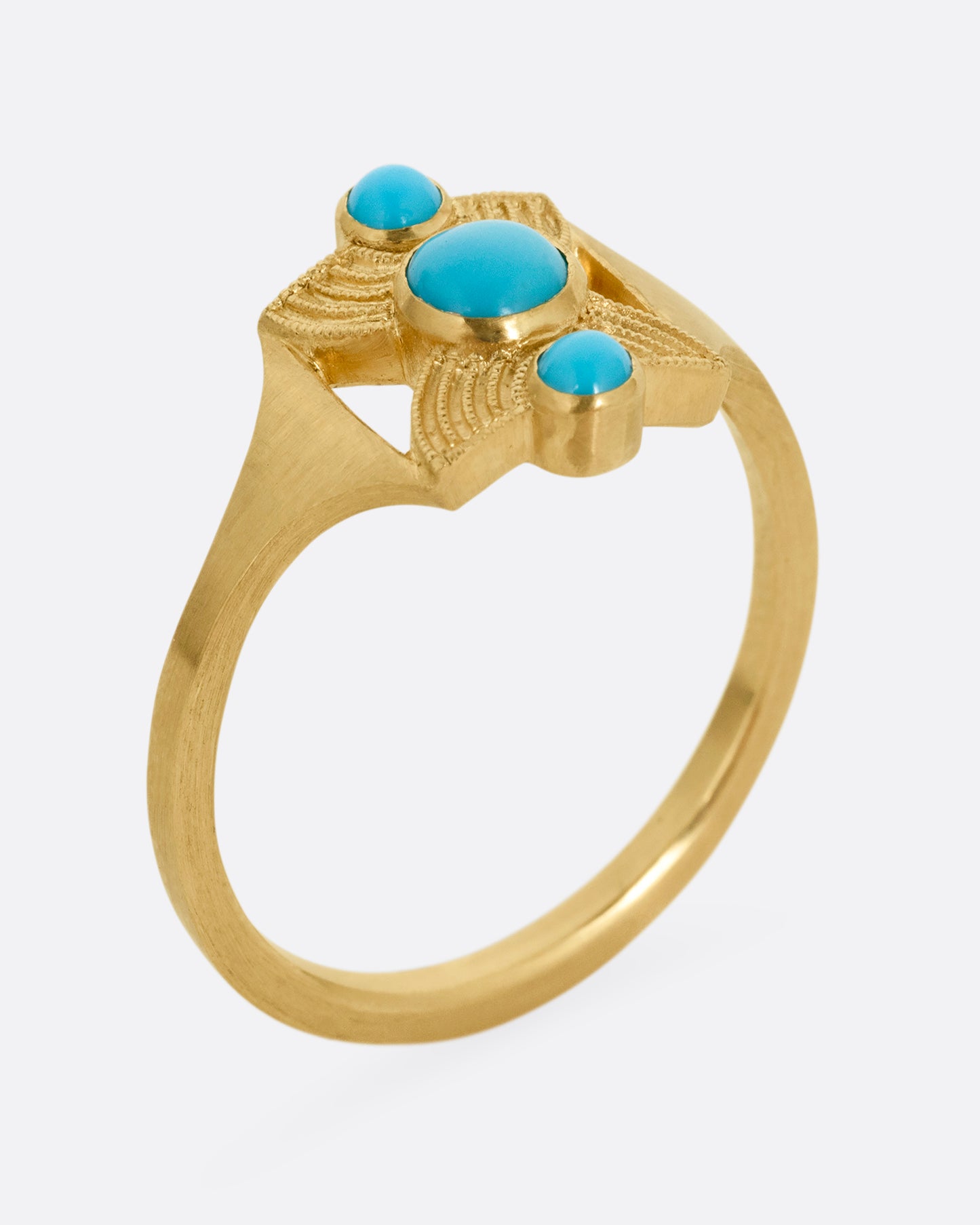 A yellow gold hourglass shaped ring with three stacked bezel set turquoises. Shown standing up from the side.