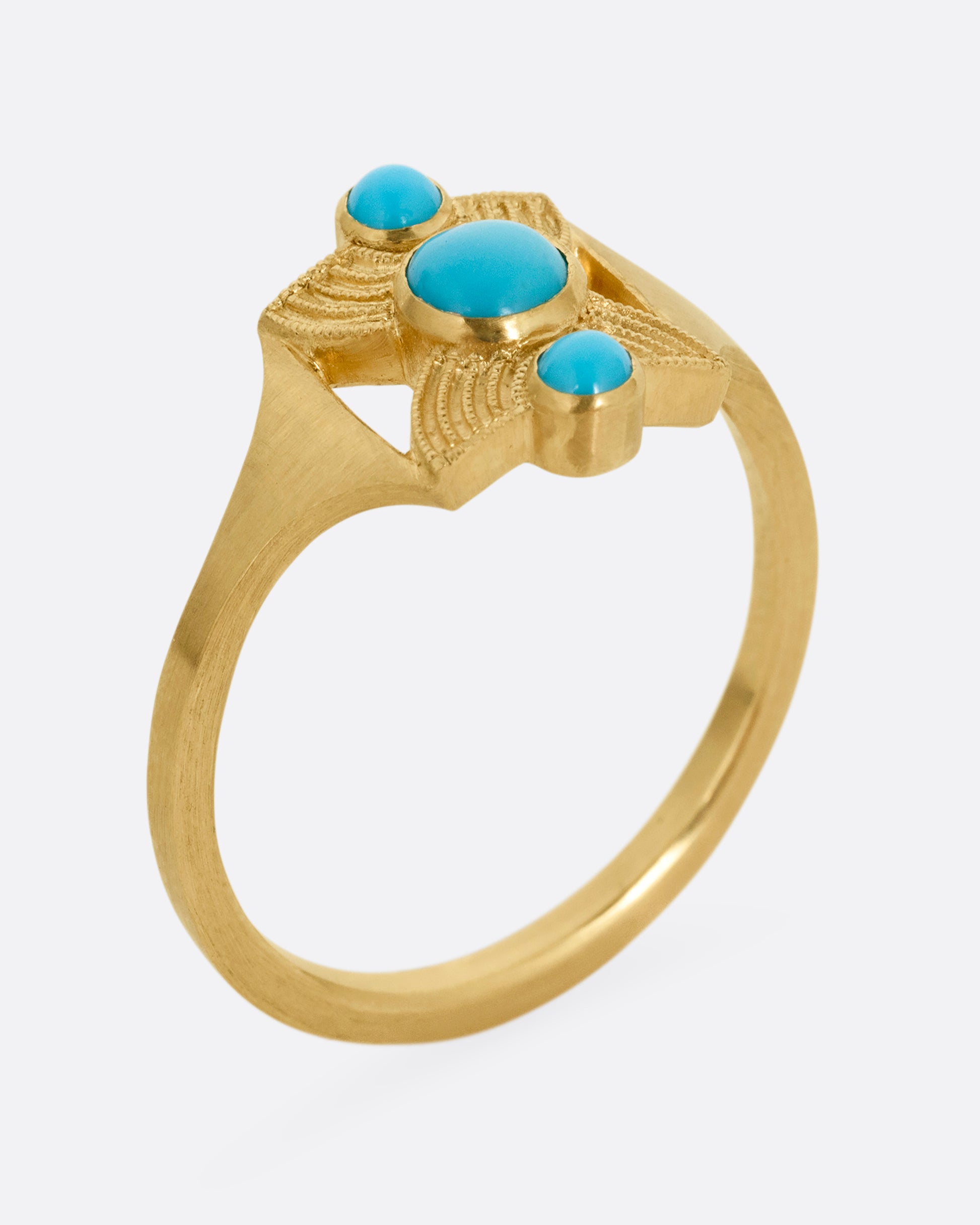 A yellow gold hourglass shaped ring with three stacked bezel set turquoises. Shown standing up from the side.