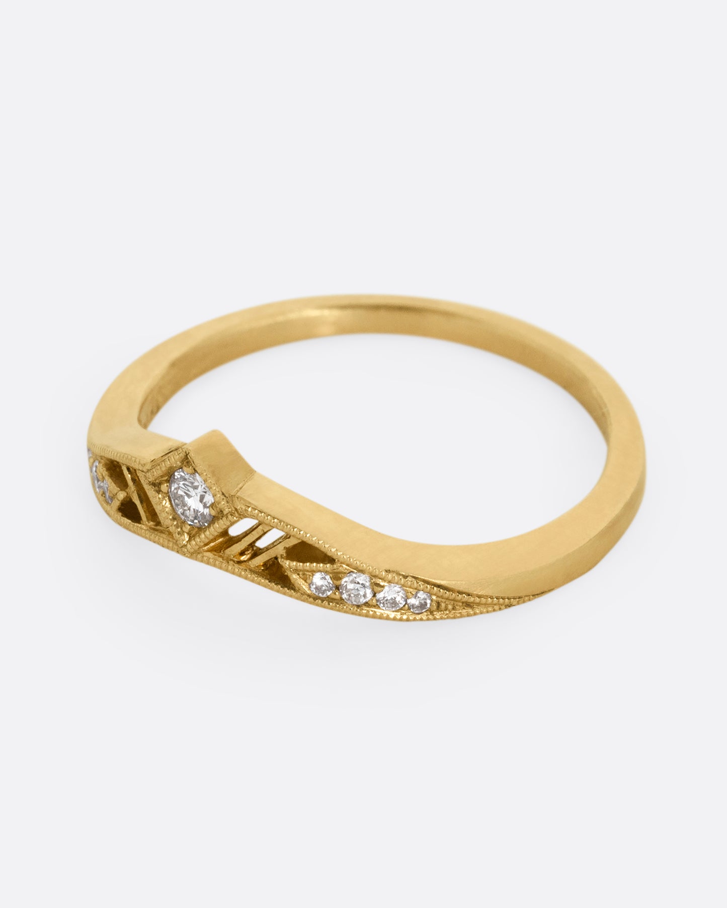 A subtly arched yellow gold ring with a diamond peak at the center flanked by graduated diamonds and cutouts. Shown from the side.