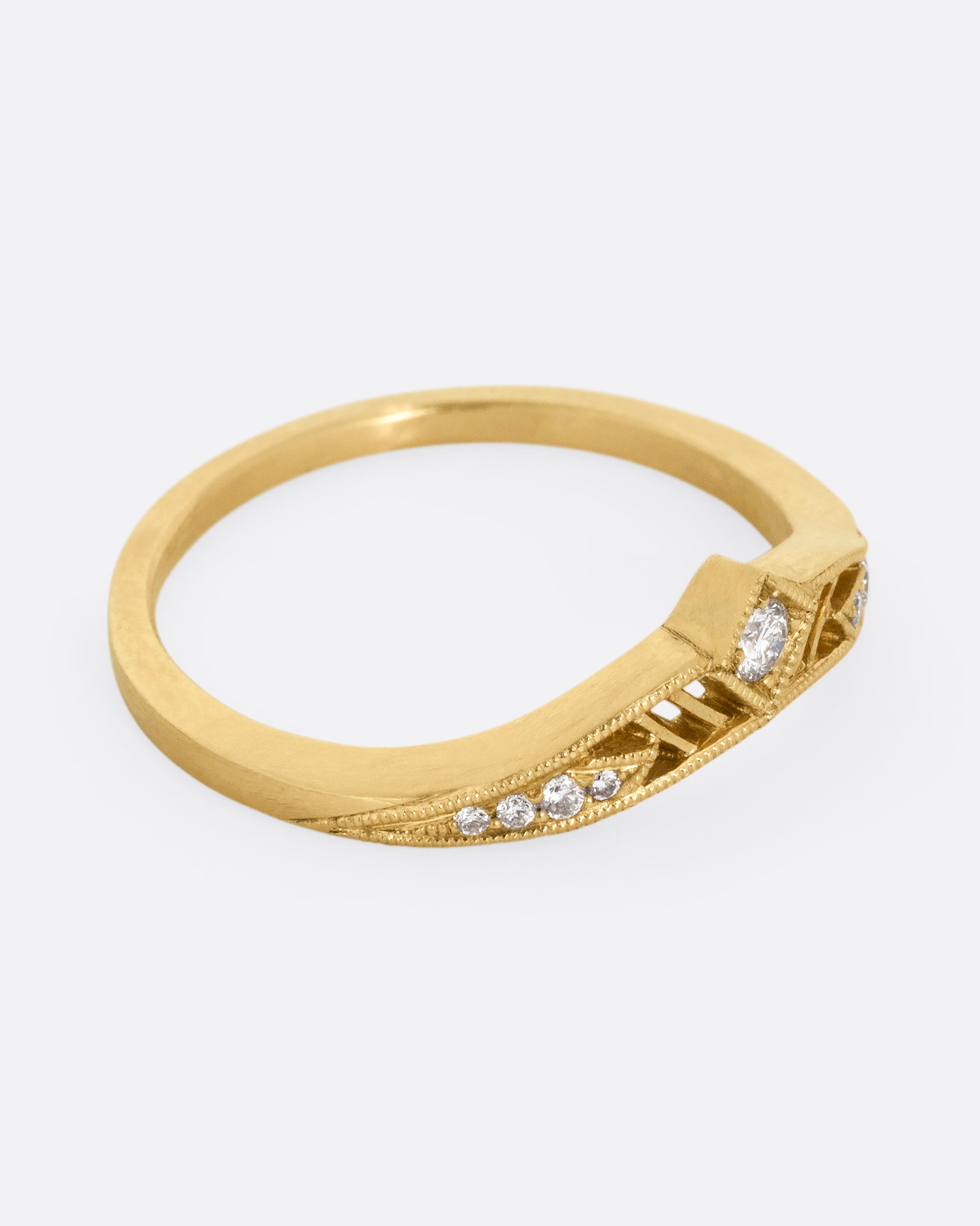 A subtly arched yellow gold ring with a diamond peak at the center flanked by graduated diamonds and cutouts. Shown from the side.