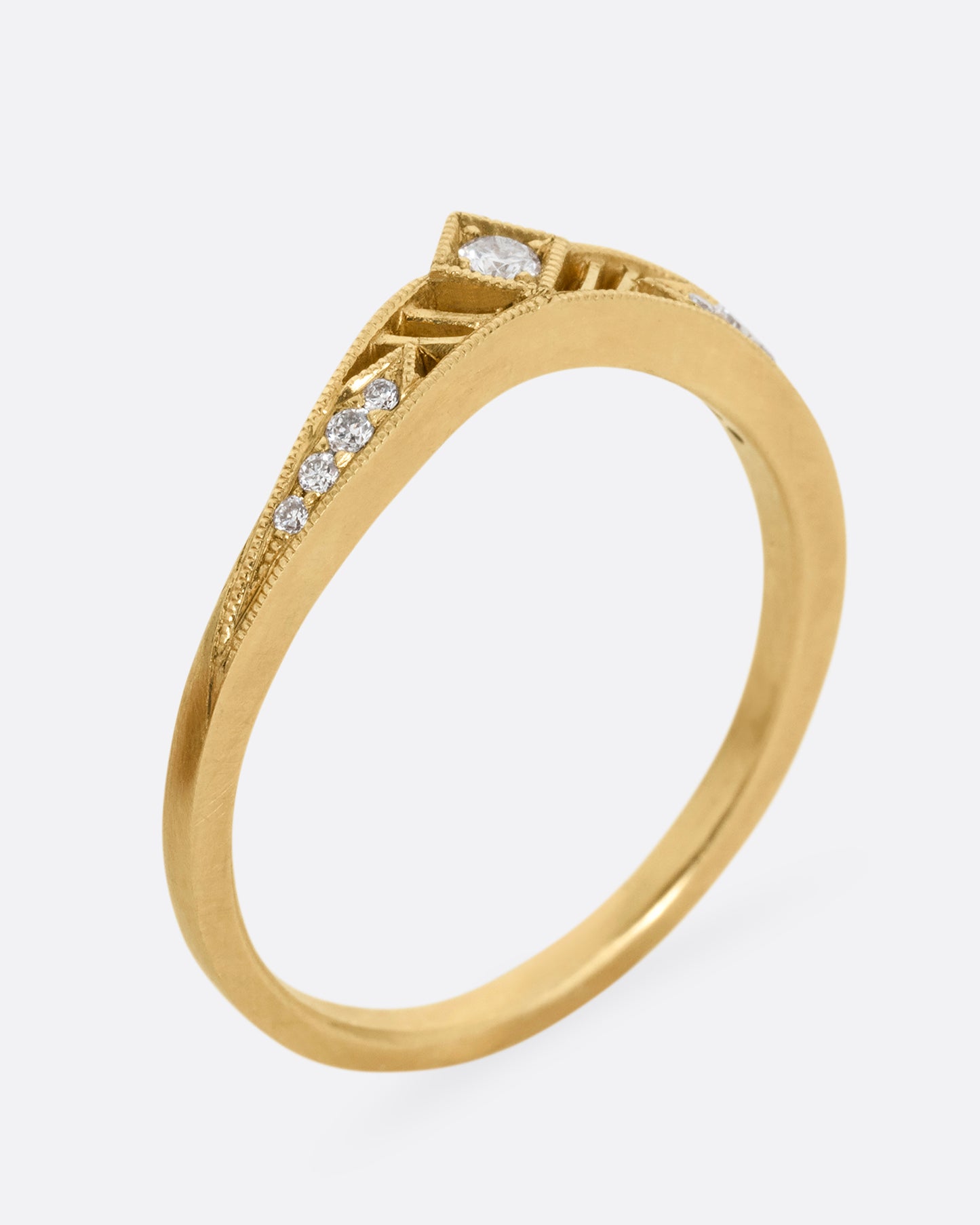 A subtly arched yellow gold ring with a diamond peak at the center flanked by graduated diamonds and cutouts. Shown standing up from the side.