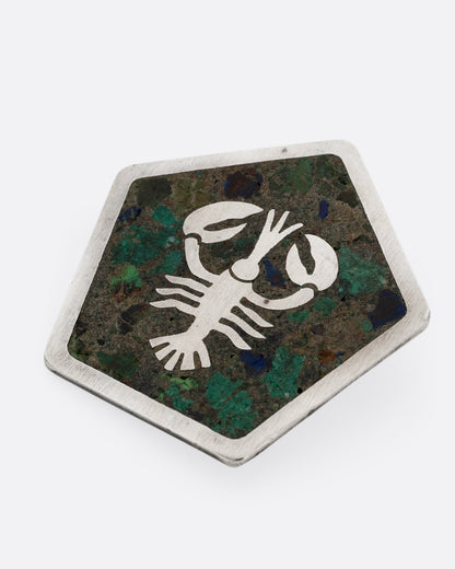 A silver pentagonal pin with a lobster set in malachite, turquoise, and lapis. Shown from the top.