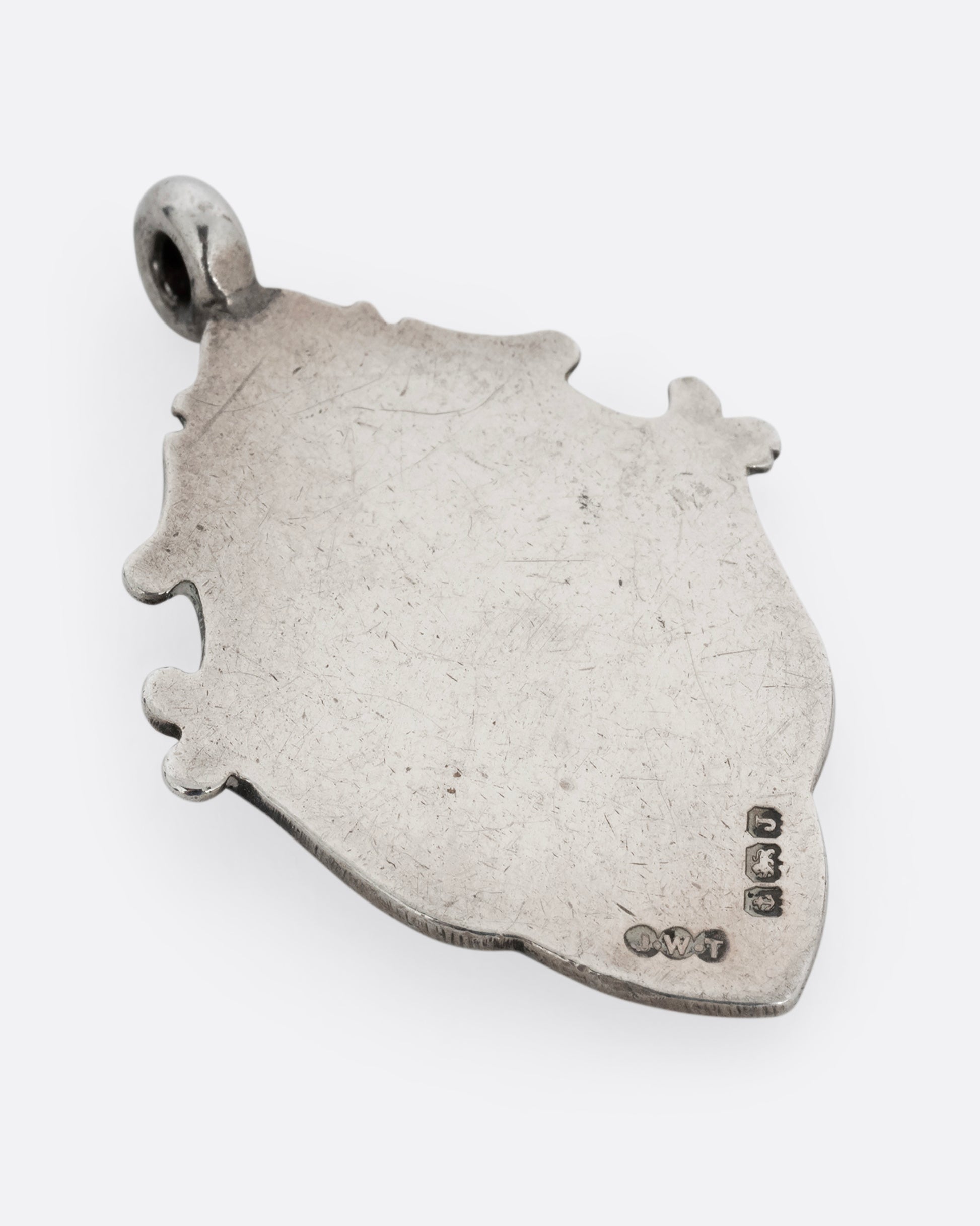 A silver billiards medal pendant with intricate scrollwork. Shown from the back.