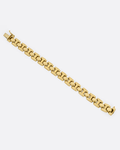 A  yellow gold bracelet with repeating oval sections. Shown from the top open and lying flat.