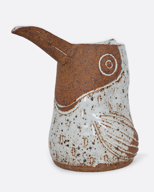 A toucan shaped pitcher with a brown face and speckled body. Shown from the side.