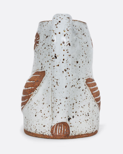 A white bird shaped pitcher with a handle. Shown from the back.