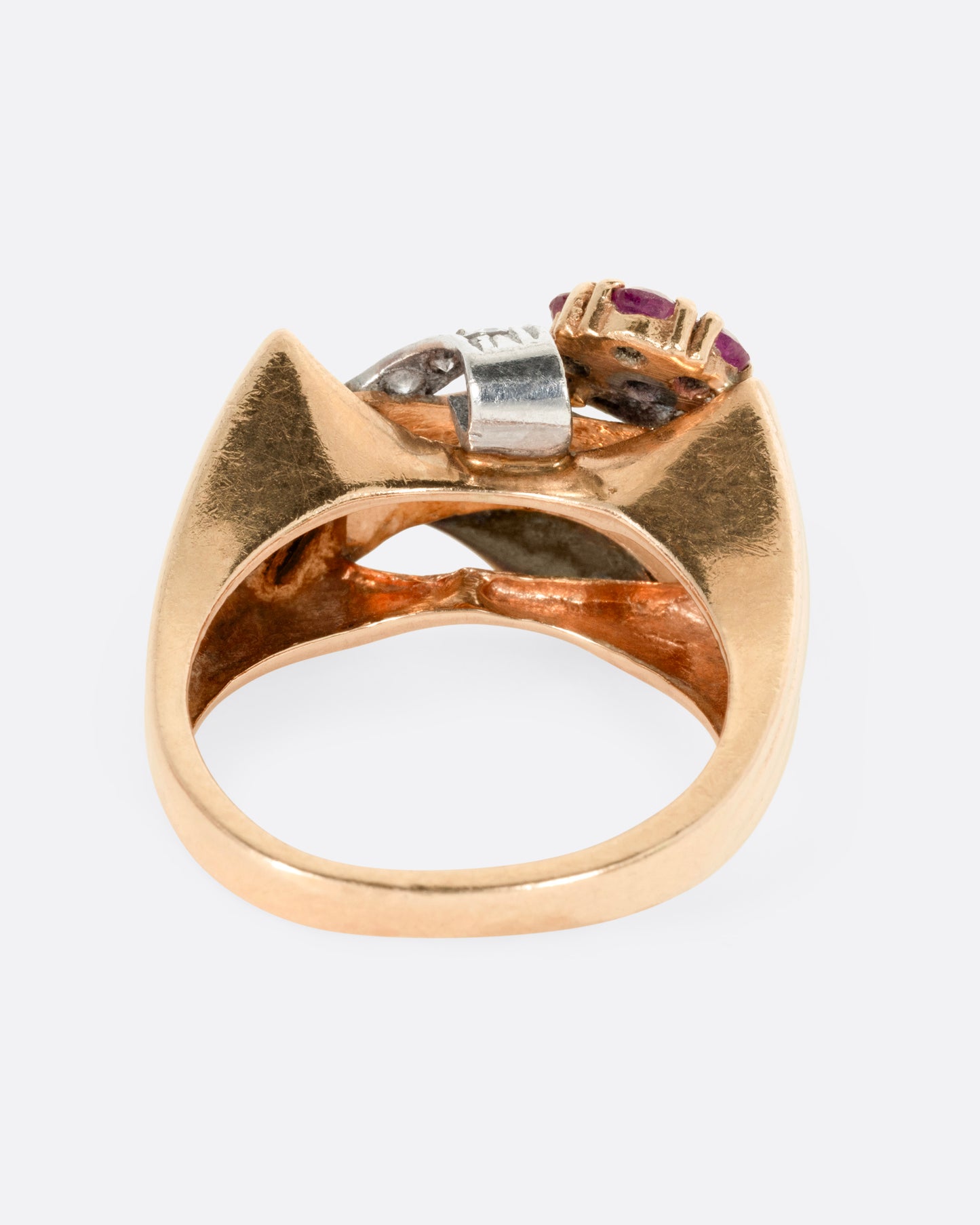 A yellow, white, and rose gold ring with ruby and diamond flowers and diamond details, shown from the back.