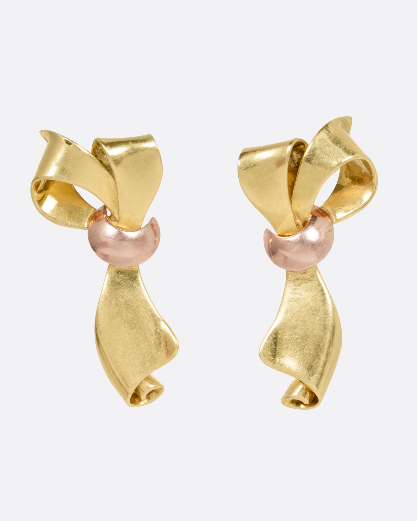 A pair of yellow gold ribbon shaped earrings with a rose gold knot, shown from the front.