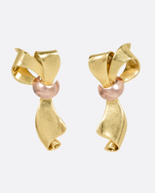 A pair of yellow gold ribbon shaped earrings with a rose gold knot, shown from the front.