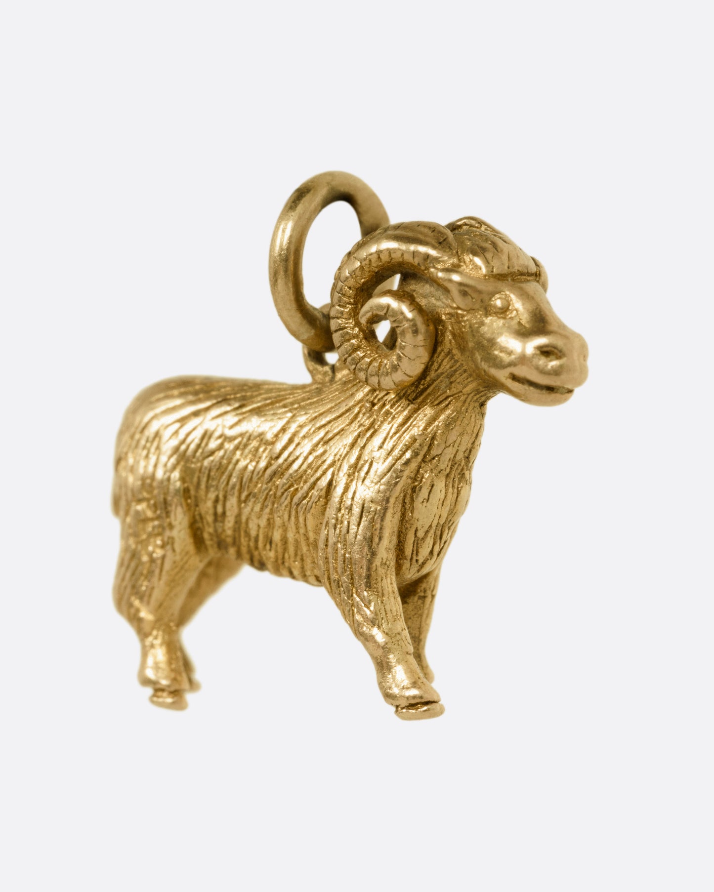 A yellow gold goat pendant, shown from the side.
