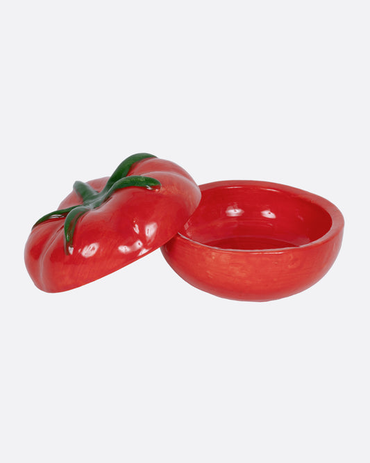 A tomato shaped salt cellar, shown from the front with the top leaning against its side.