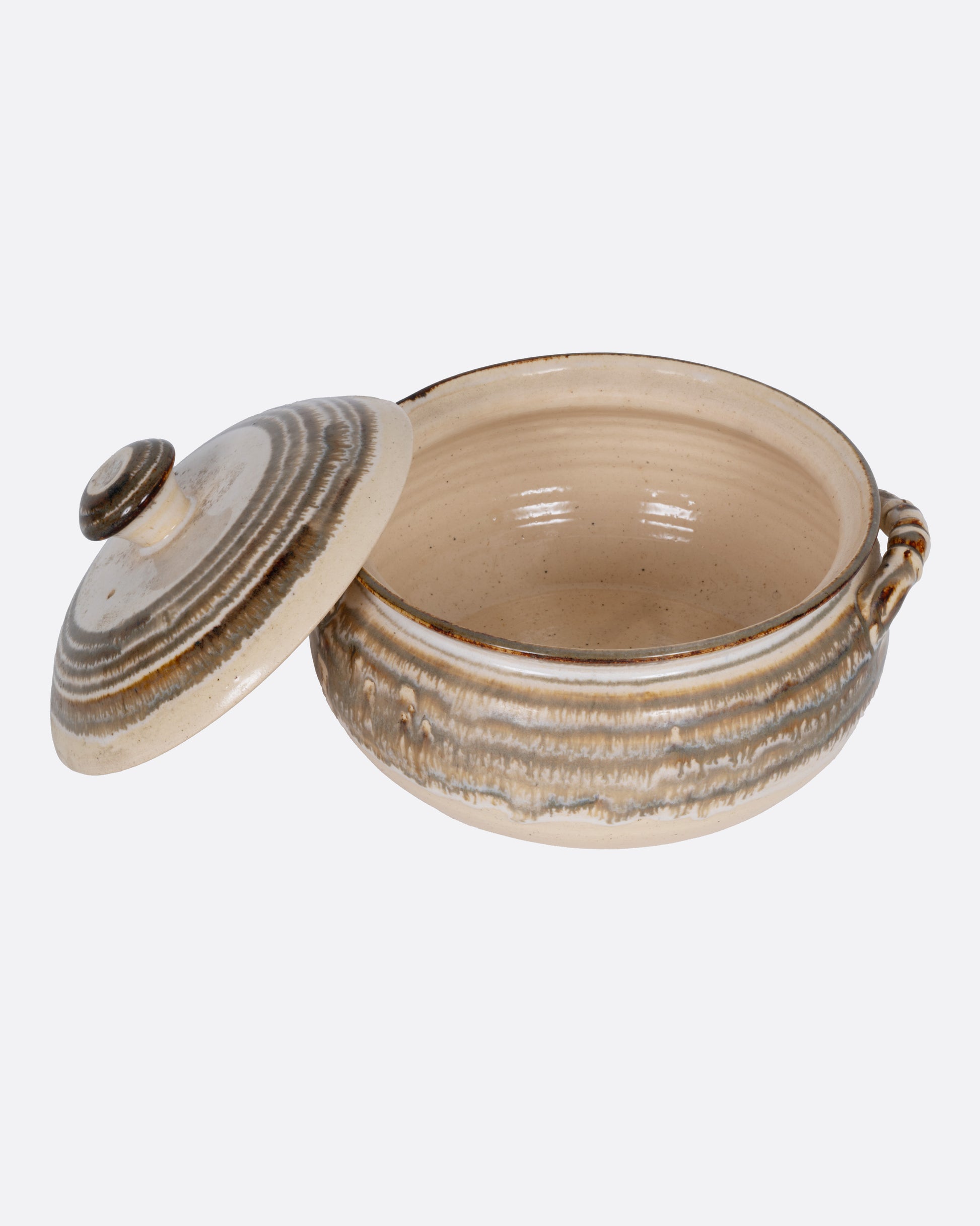 A beige striped casserole dish with dual handles and a domed lid, shown from the front with its lid leaning on the side.