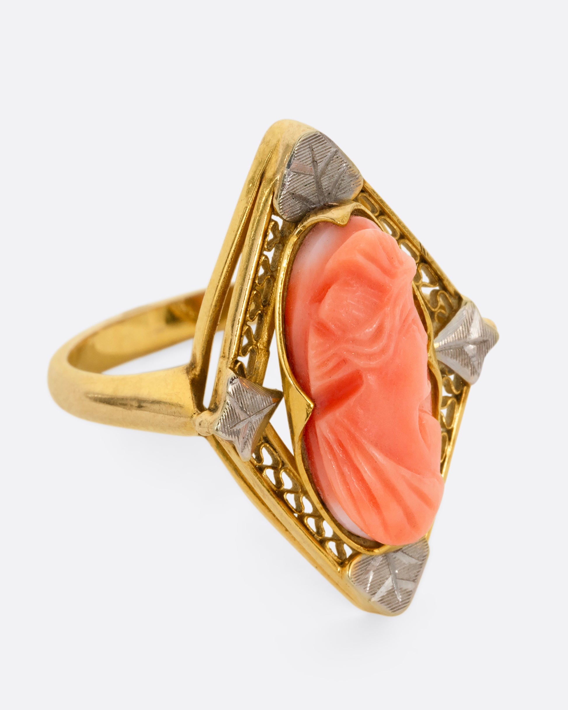 A yellow gold cameo ring with a coral carved portrait. Shown from the side.
