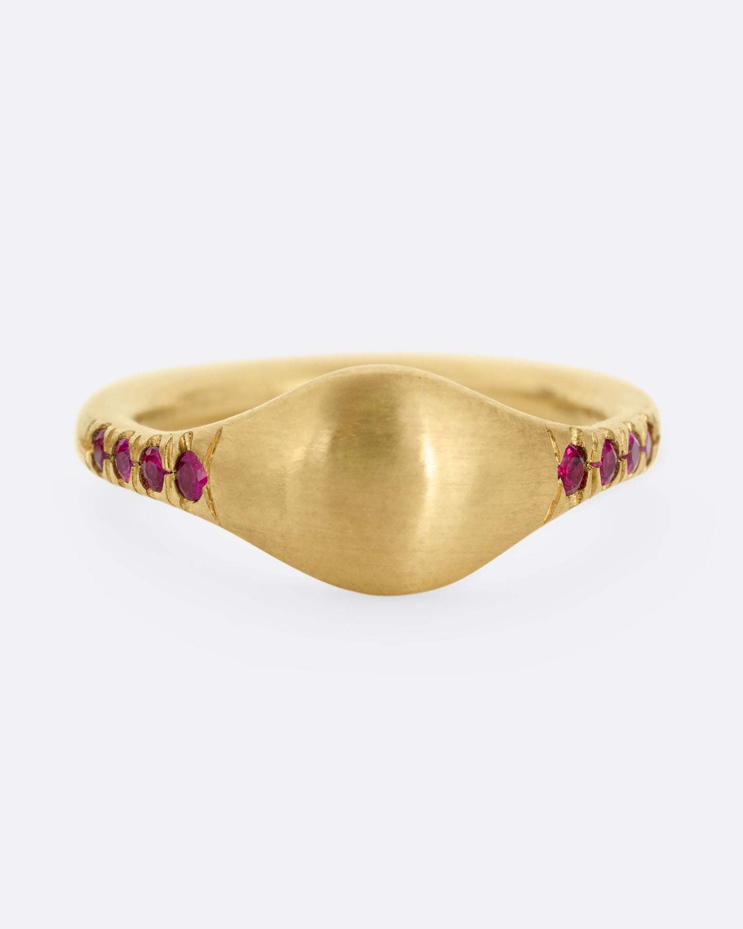 A yellow gold signet ring with rubies on the shoulders. Shown from the front.