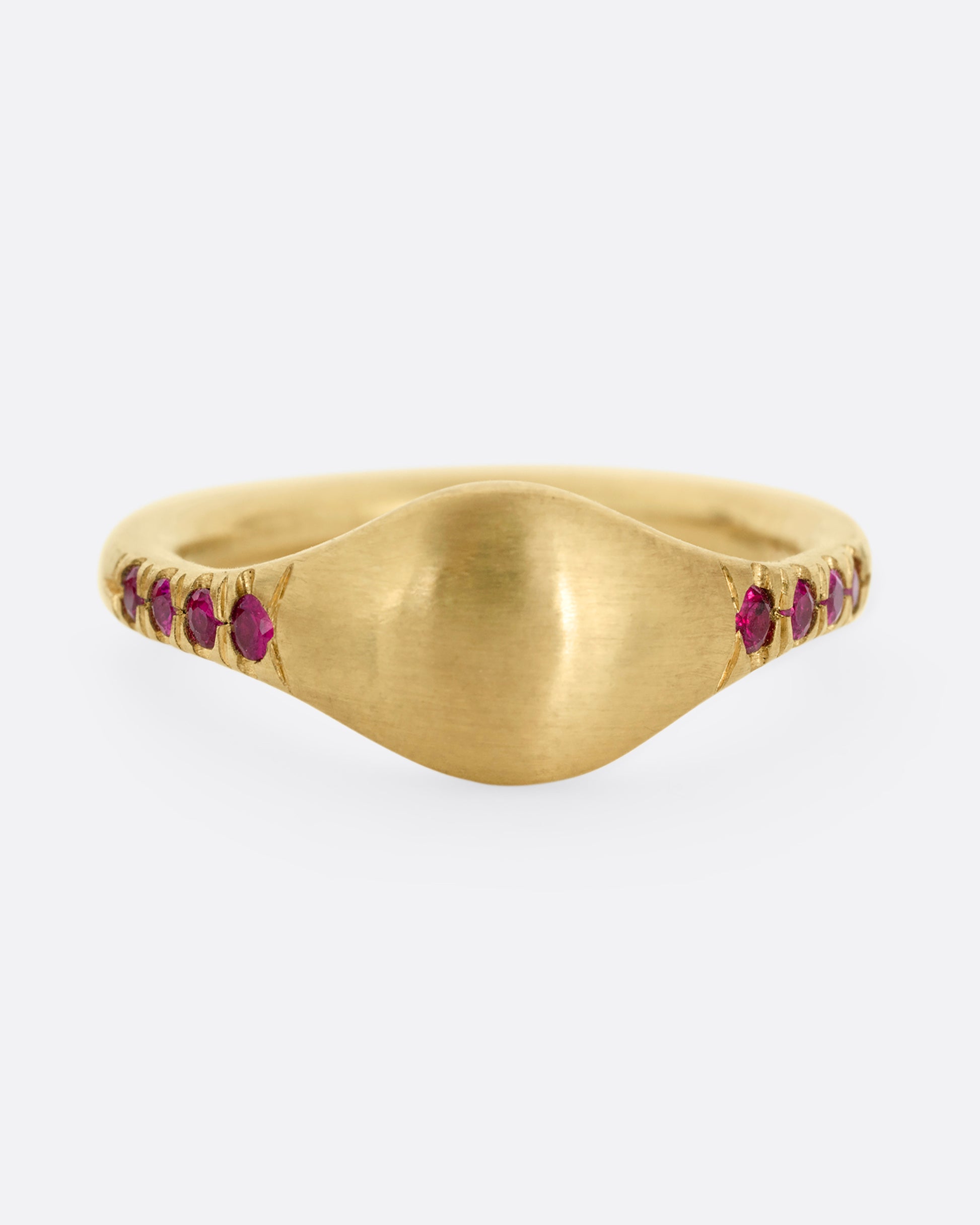 A yellow gold signet ring with rubies on the shoulders. Shown from the front.