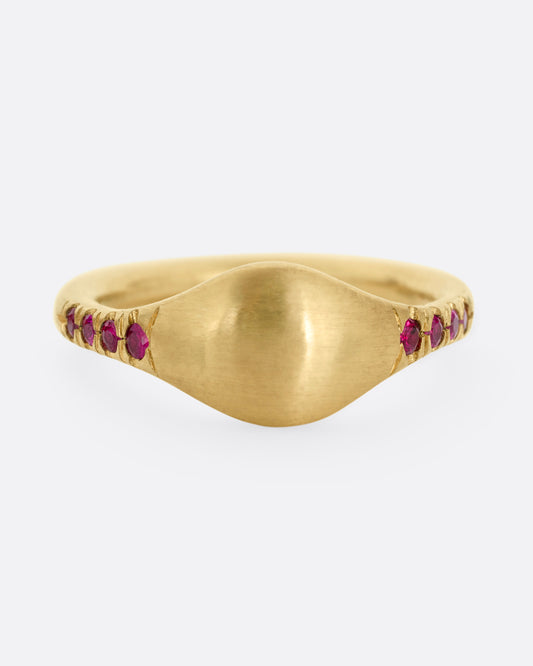 A yellow gold signet ring with rubies on the shoulders. Shown from the front.