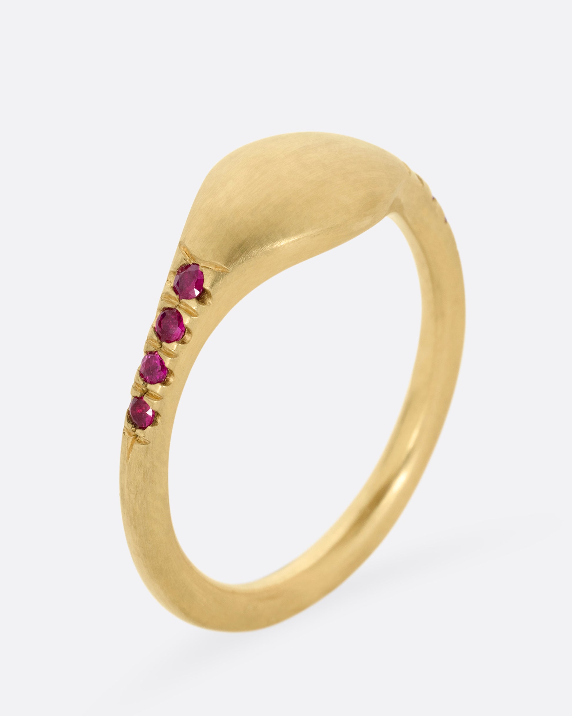 A yellow gold signet ring with rubies on the shoulders. Shown standing up from the side.