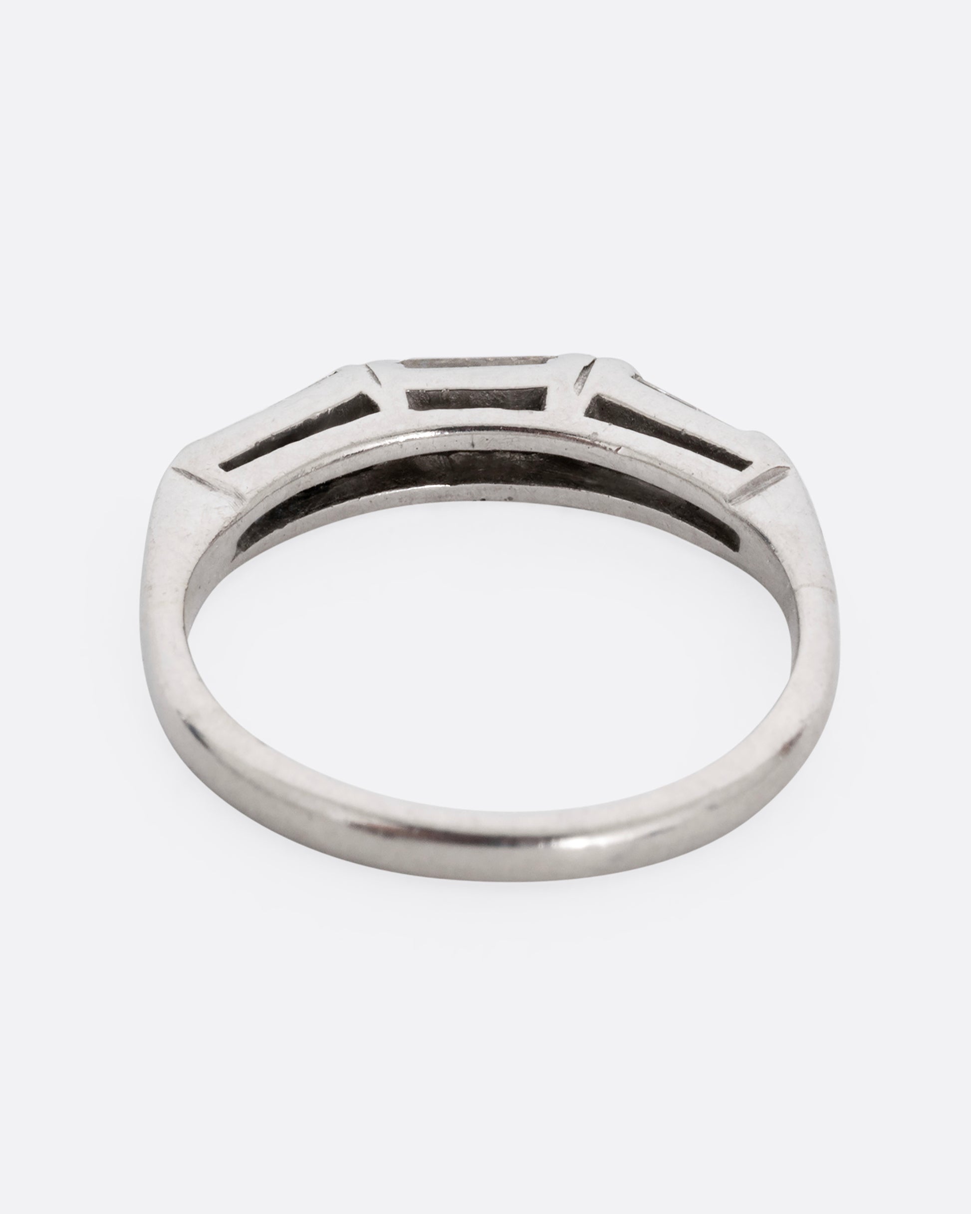 A platinum ring with three baguette diamonds. Shown from the back.